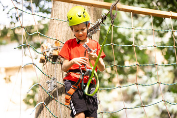 Cute school boy enjoying a sunny day in a climbing adventure activity park