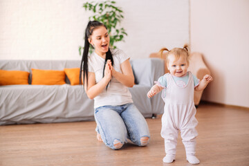 a little girl takes her first steps at home and her mother is very happy with her daughter's success. the concept of a healthy child