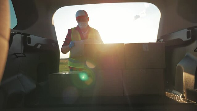 Delivery driver loading his van with boxes. Professional mover loads it cardboard boxes in car. Goods transportation and shipping.
