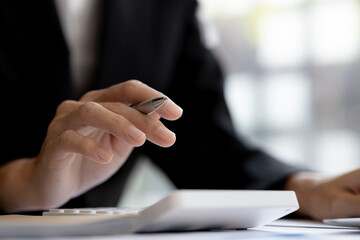 Business woman using a calculator to calculate numbers on a company's financial documents, he is analyzing historical financial data to plan how to grow the company. Financial concept.