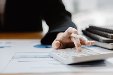 Business woman using a calculator to calculate numbers on a company's financial documents, he is analyzing historical financial data to plan how to grow the company. Financial concept.