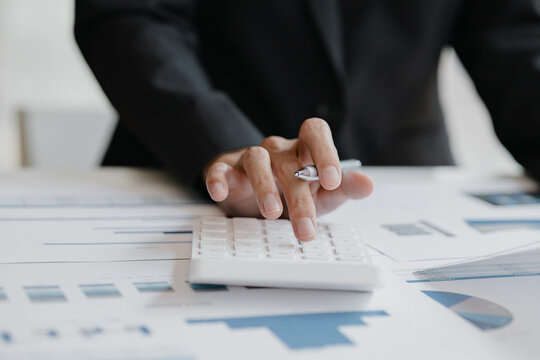 Business woman using a calculator to calculate numbers on a company's financial documents, he is analyzing historical financial data to plan how to grow the company. Financial concept.