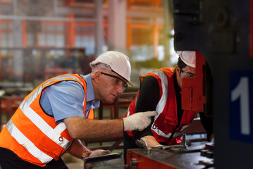 Fototapeta premium Male engineer caucasian inspects the operation of industrial machines in an industrial plant.