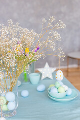 Table with Easter decor in soft pastel colors with branches of white gypsophila.