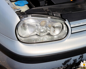 Car headlights and open hood. Exterior detail close-up. Details of an old car