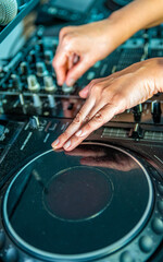 DJ Hands creating and regulating music on dj console mixer in concert nightclub