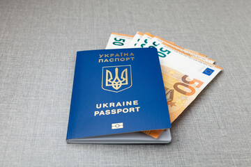 Ukrainian passport with european money euro on gray table background. Refugees protection concept.
