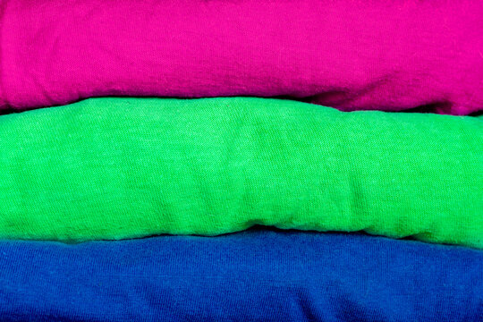 A stack of clothes folded in the colors of the polisexual community flag. Background with place for text for a template on the theme of tolerance and gender diversity