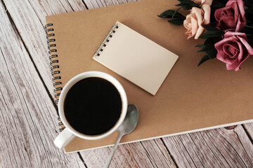 black coffee with notebook and rose on wooden table
