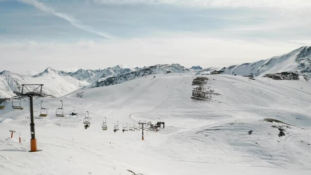 Livigno, Italy - February 21, 2022: aerial view of Livigno ski resort in Lombardy, Italy. Chairlifts, ski lifts, gondola cabin are moving and skiers skiing over scenery panorama. 4k video footage 
