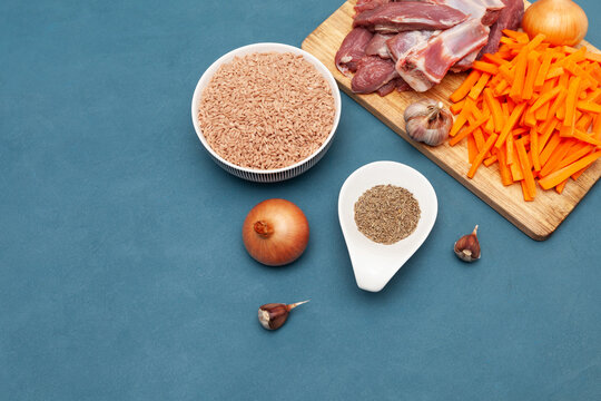 Raw food, pilaf. Ingredients for pilaf, meat lamb, Devzira rice, cumin, garlic and carrots on wooden cutting board. Oriental cuisine