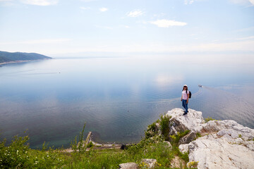 Obraz premium A woman is traveling on Lake Baikal. Beautiful view from the cliff at the port of Baikal on a summer day. 