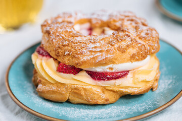 Traditional French Dessert called Paris Brest on a light grey background with powder sugar and...