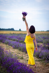 Ukrainian girl in a yellow suit picked up a bouquet of lavender on the field. Purple is a very beautiful color. Selective focus