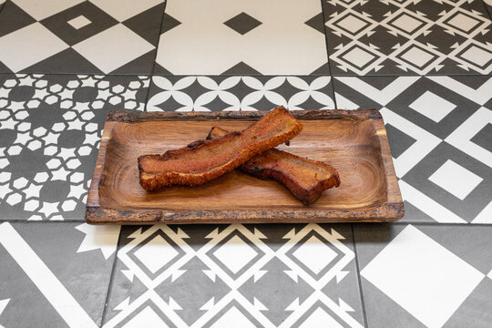Two wonderful strips of fried torrezno Soria style on a wooden tray
