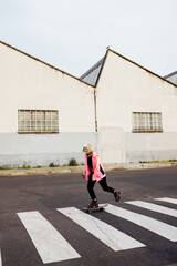 Nonconformist young woman rebel outdoors skating riding skateboard in the city