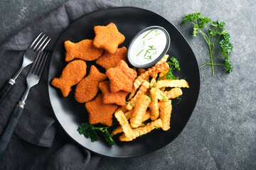 Fish Chips british fast food. Fish Sticks with french fries set on black plate on black table background. Traditional British authentic street food or takeaway food. Mock up with space for text.
