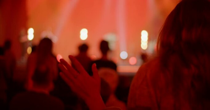 Female Christian Worships and Praises God on Music Concert, Youth Festival or Conference. Christian Believers Sing Songs with Raised Hands on Live Stage Event. 4K backside view handheld shot