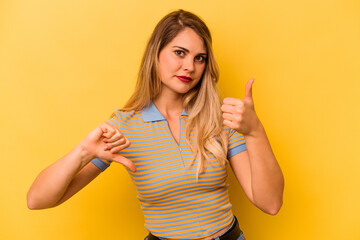 Young caucasian woman isolated on yellow background showing thumbs up and thumbs down, difficult...