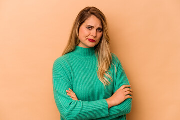 Fototapeta premium Young caucasian woman isolated on beige background suspicious, uncertain, examining you.