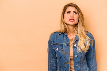 Young caucasian woman isolated on beige background shouting very angry, rage concept, frustrated.