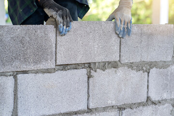 masonry worker make concrete wall by cement block and plaster at construction site