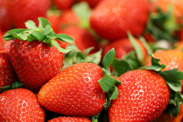 Fresh red strawberries with leaves. Pile of ripe strawberry for background