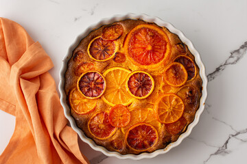 Sweet pie with caramelized citrus fruits in a round ceramic form, top view