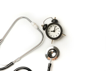 Stethoscope and alarm clock isolated on white background closeup. The concept of the need for timely medical diagnosis.