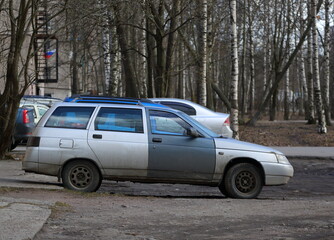 Obraz premium Old light silver car with dark door, Iskrovsky Prospekt, St. Petersburg, Russia, April 2022
