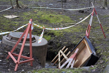 Wooden barrier enclosing the sinkhole at the sewer manhole