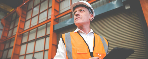 Factory engineer male in hard hat helmet working on digital teblet computer at Heavy Industry...
