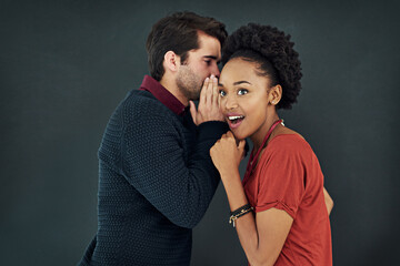 I heard were getting bonuses next month. Cropped shot of two people gossiping against a dark background.