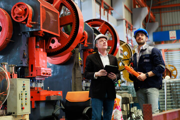 lathe and stamping metal machine. Caucasian business man and Factory engineer in hard hat helmet...