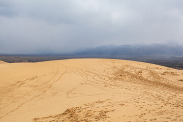 Sarykum dune. Dagestan, Russia. A unique sandy mountain in the Caucasus on a cloudy day. Grass grows on a sand dune.