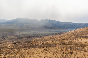 Sarykum dune. Dagestan, Russia. A unique sandy mountain in the Caucasus on a cloudy day. Grass grows on a sand dune.