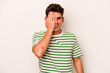 Young caucasian man isolated on white background having fun covering half of face with palm.
