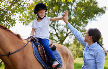 Today was a good session. Shot of young girl with her instructor with a horse outdoors in a forest.