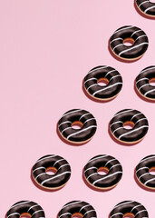 Chocolate rings. Top view photo. Classic donuts with icing on pastel pink backdrop