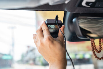 Hand of technician installing front camera car recorder on windscreen