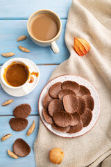 Chocolate chips with cup of coffee and caramel on a blue wooden background. top view, close up.