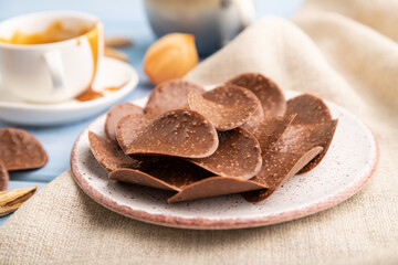 Chocolate chips with cup of coffee and caramel on a blue wooden background. side view, close up, selective focus.