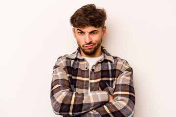 Fototapeta premium Young hispanic man isolated on white background frowning face in displeasure, keeps arms folded.
