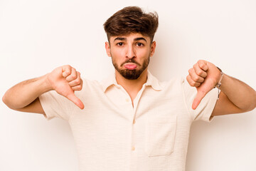 Young hispanic man isolated on white background showing a dislike gesture, thumbs down....