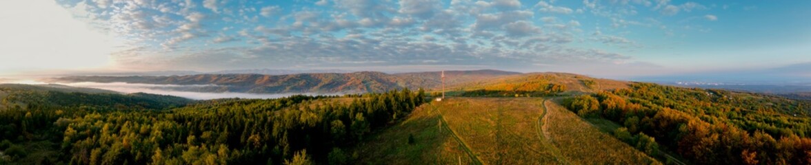 Beautiful autumn panorama of yellow and red trees against the background of big mountains