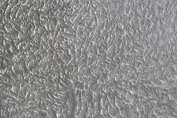 The grainy texture of wall plaster.