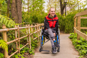 Portrait of a person with a disability in a public park in the city. Sitting in the wheelchair...