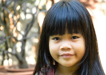 Front view, a portrait of a cute little Asian girl with black hair smiling and looking at a camera. Holiday, happy and healthy child concept