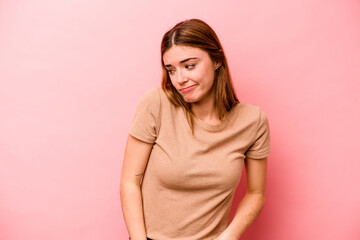 Young caucasian woman isolated on pink background shrugs shoulders and open eyes confused.