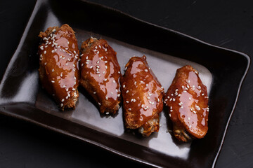 Fried chicken wings with spicy and sweet Korean sauce topped with white sesame seeds